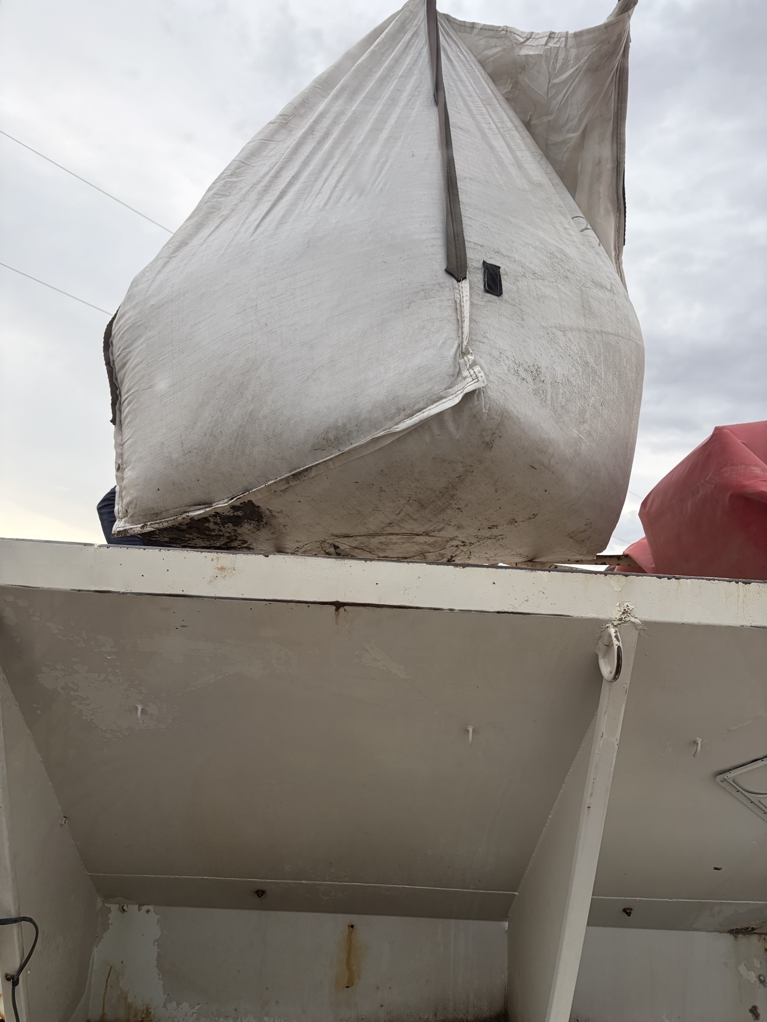 White super sack suspended above a spreader hopper during loading