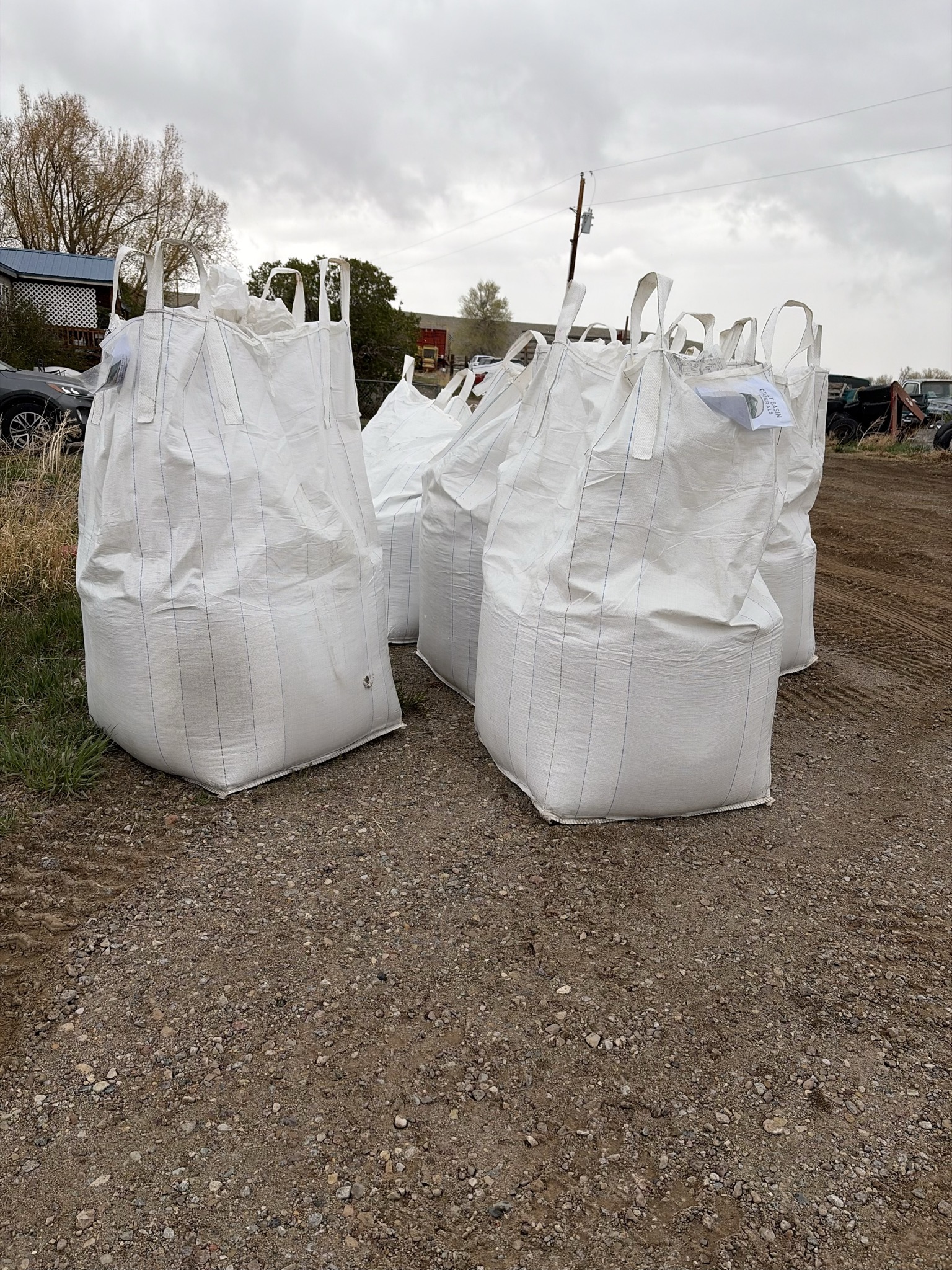 Multiple white super sacks staged on a farm lot